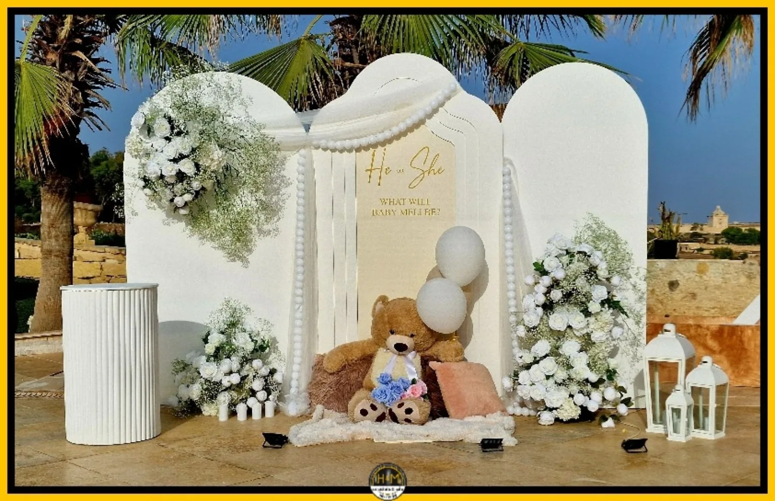 Gender reveal décor with elegant white backdrop and floral styling by Handcrafts & More